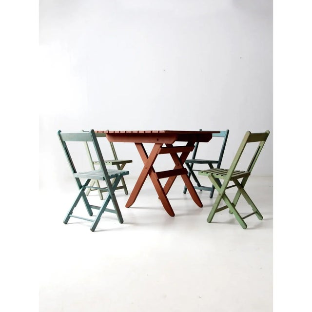Vintage wooden patio set featuring a folding slat wood table and four coordinating folding chairs, designed for both...