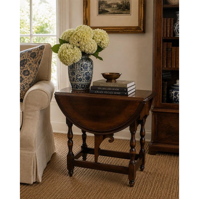 A handsome Jacobean-style drop leaf side table crafted in rich solid walnut. The elegant turned legs and butterfly...