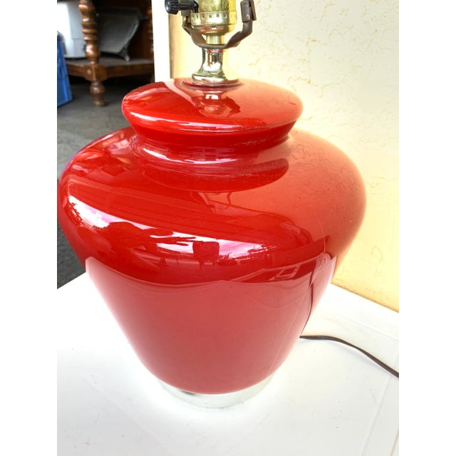 Deep Red glass table lamp. The lamp is 24” tall with the top of the harp widest part of the body is about 11” wide. The...