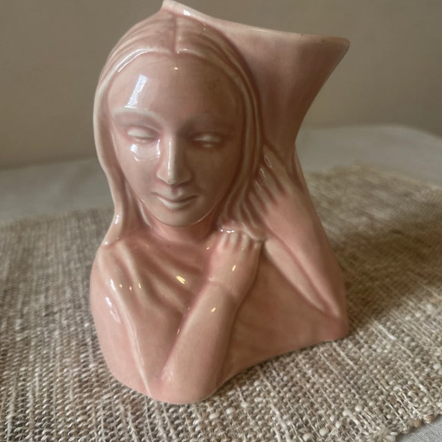 This charming vintage vase is a beautiful example of Hull Pottery craftsmanship, showcasing a delicate pink glaze and...