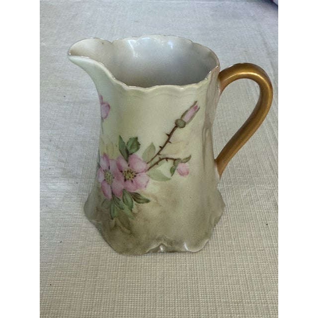 This vintage Hutschenreuther Selb porcelain creamer features hand-painted floral motifs, 22-24K gold gilding, and a...