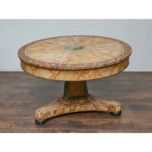An Italian Neoclassical style faux marble painted center table from the 19th century with circular top and pedestal base....