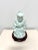 An Asian style Buddha figurine with wood stand by Andrea by Sadek. Hand painted, light blue color glazed porcelain of a...