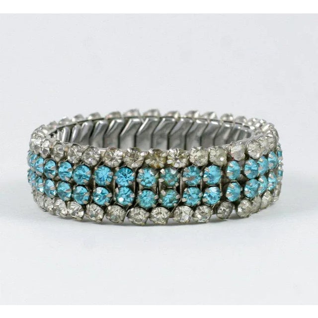 This is part of Chairish’s Costume Jewelry assortment. 1940's stretch metal bracelet of clear and turquoise rhinestones.