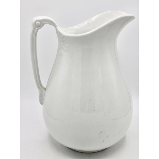 A lovely, large ironstone white pitcher. Perfect farmhouse decor! It works as a pitcher or a vase. Beautiful design on the...
