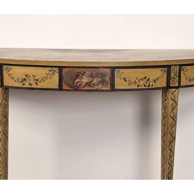 A George III style fancy painted demilune console, circa 1920. This fancy painted style was first done. by Robert Adams in...