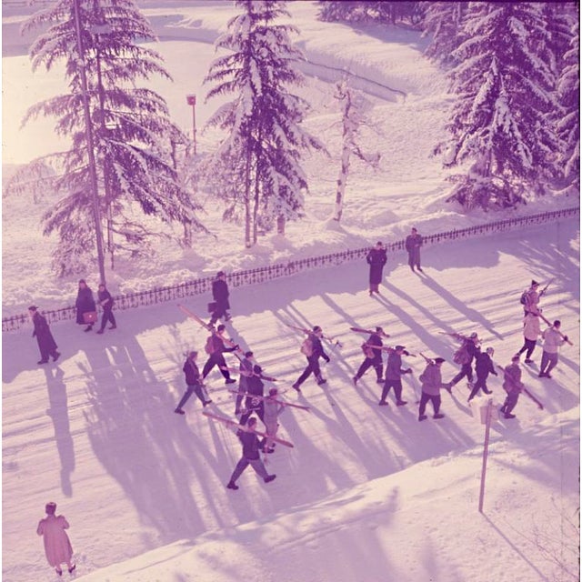 Setting Out 1954 A group of skiers walk through the street on their way to the ski runs, Klosters, Switzerland, 1954. Toni...