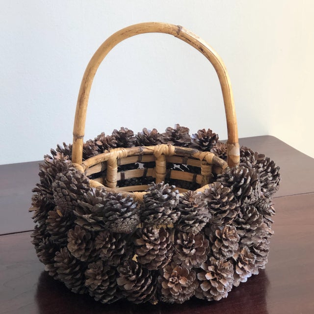 Offering a beautiful hand-crafted, Adirondack-style bamboo and pine cone basket. This exquisite basket features a bamboo...