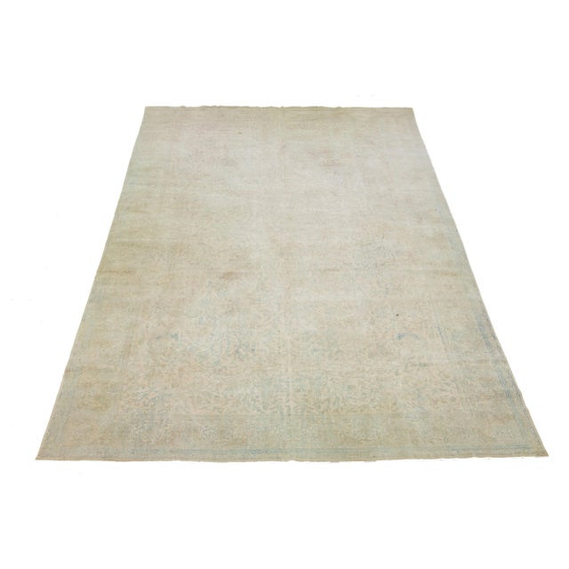 This beautiful hand-knotted, antique Agra wool rug has a tan-beige color field. The rug hails from India and features blue...