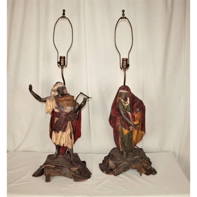 A rare pair of antique lamps in the figures of a Moroccan male playing a stringed instrument and a Moroccan female...