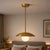 Crafted from solid brass, this pendant light features a clean disc-shaped shade paired with a softly illuminated opal...