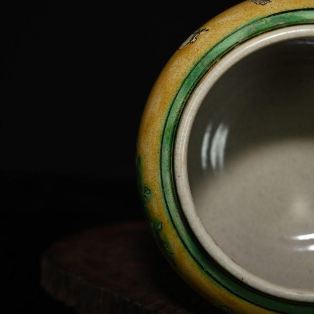 This charming ceramic jar features a warm, mustard-yellow glazed background adorned with a hand-painted scene of...