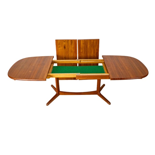 Classic Danish teak dining table featuring a sculptural trestle base and a clever draw-leaf extension system. Unlike the...