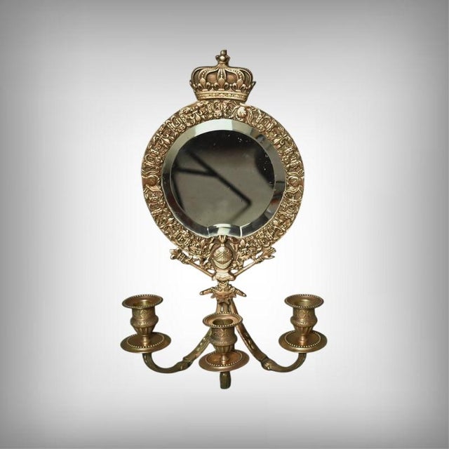 A pair of wall sconces combining mirrors and candle holders, crafted in gilt bronze in the neoclassical style. Each sconce...