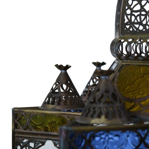 A vintage Moroccan chandelier of pierced metalwork inset with jewel-toned glass — cobalt, emerald, amber, and ruby panels...
