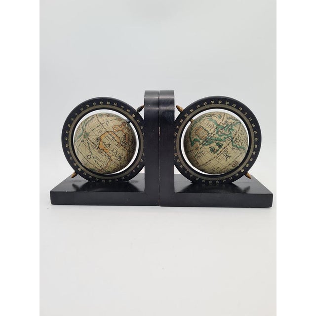 A decorative pair of bookends with miniature globes featuring a degree scale, inspired by the form of an armillary sphere....