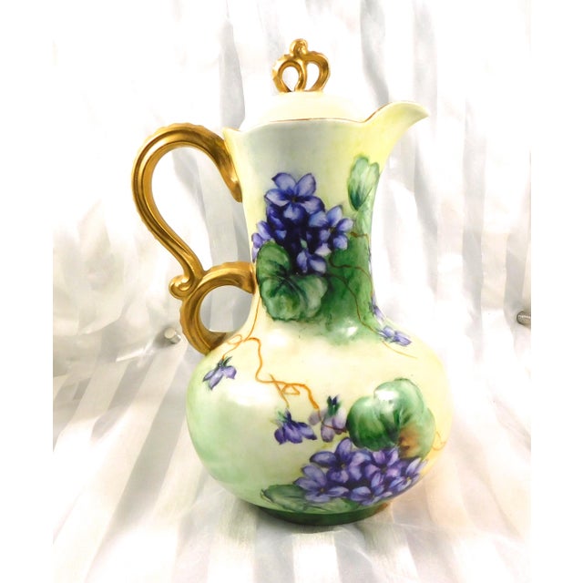 This is a green Jean Pouyat Limgoes chocoalte pot or teapot with what I believe are hand painted purple flowers, a...