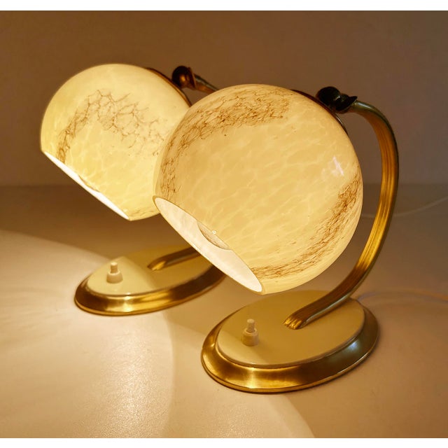 Pair of Art deco table lamps featuring an oval brass base with ivory enamel highlight, ribbed / plain brass craddle stem...