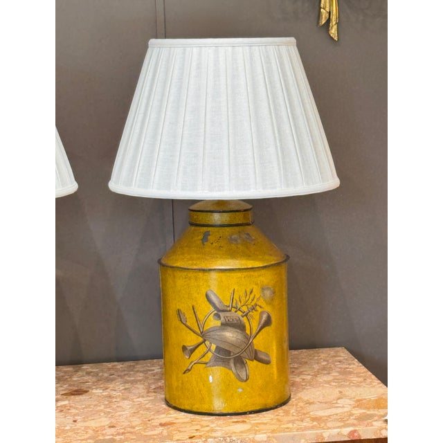 A pair of early 20th century French tole tea canisters, later converted into table lamps. The cylindrical forms feature...