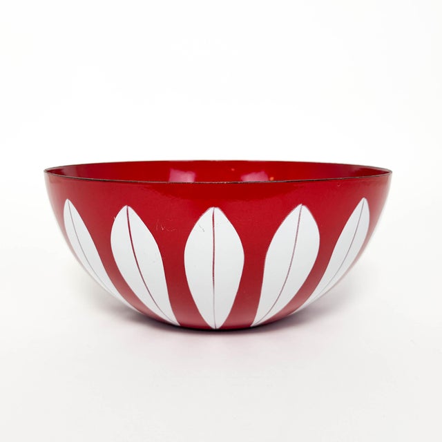 An original 11-inch Cathrineholm enameled steel bowl featuring the iconic white Lotus pattern against a vibrant red...