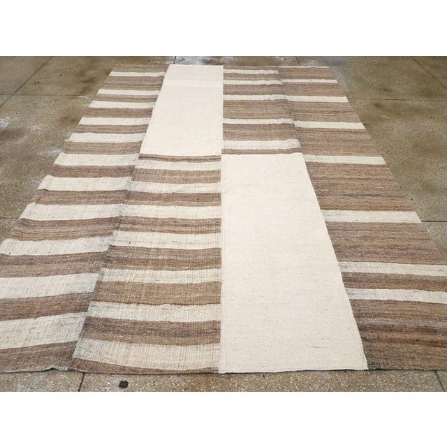 This Mid-20th century Turkish Flatweave Kilim rug, showcases a bold and graphic composition that highlights the beauty of...
