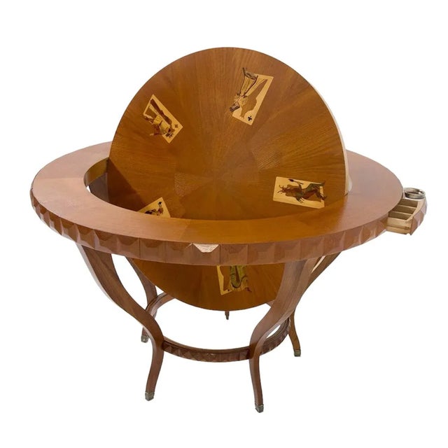 Circular table, entirely in wood. It has a double top: 1 with wooden inlays, depicting playing cards, while the other is...