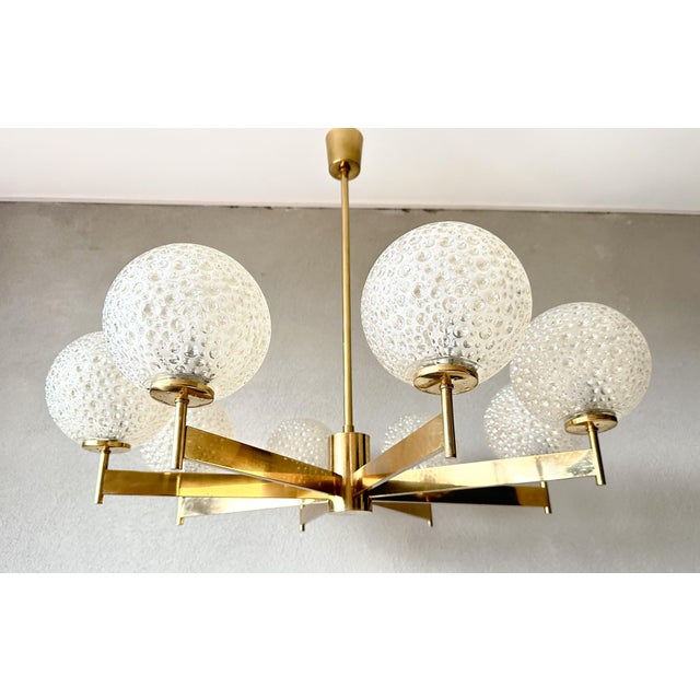 Beautiful mid-century design. Large 1970s chandelier. Brass base with eight sleek geometric arms. Finished with heavy,...