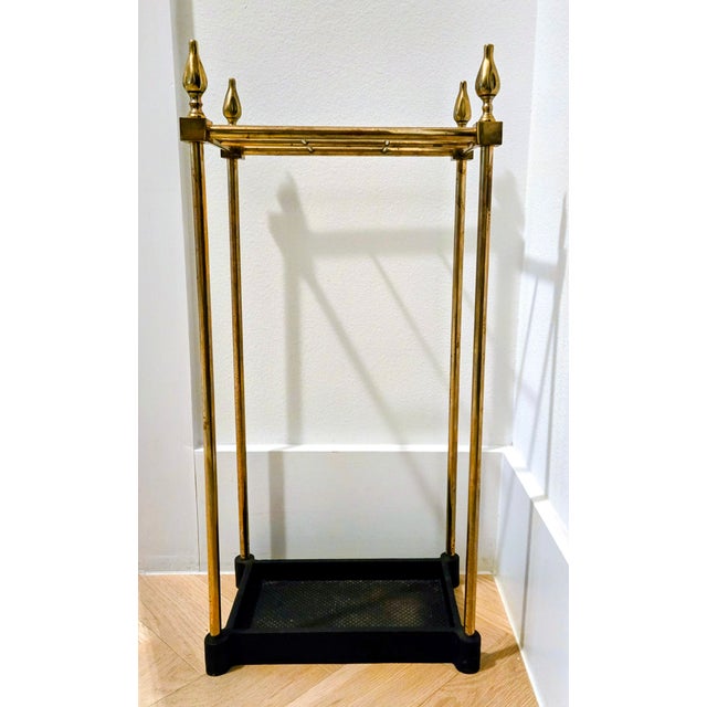 Elegant vintage umbrella stand featuring a solid cast iron drip tray base and warm brass frame with four decorative flame-...
