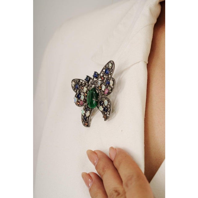 Crafted in 925 sterling silver, this striking butterfly brooch pendant showcases 17.62 carats of vibrant multi-gemstones...