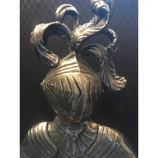 An umbrella stand in the form of a knight in a suit of armor. The knight holds a bar over the patera-form pan