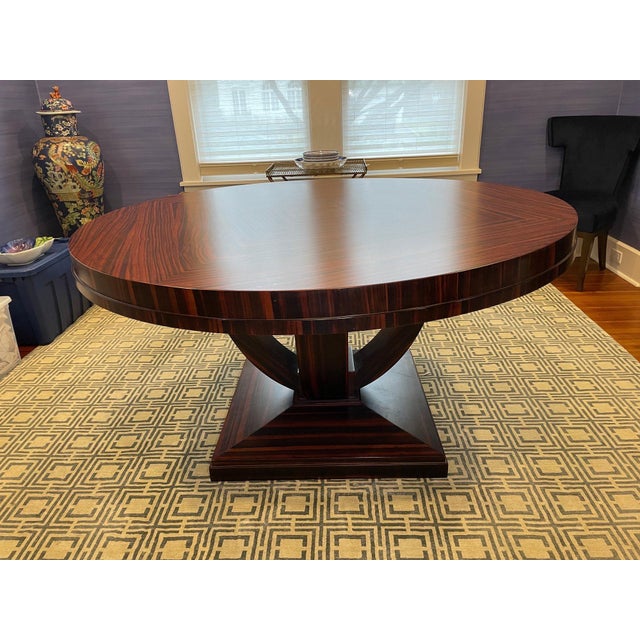 A vintage Art Deco style round dining or center hall table with a square base and curved supports in Macassar ebony wood,...