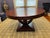A vintage Art Deco style round dining or center hall table with a square base and curved supports in Macassar ebony wood,...