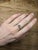 A padparadscha sapphire glows in its signature blend of pink and orange at the centre of this solid 14K white gold ring,...