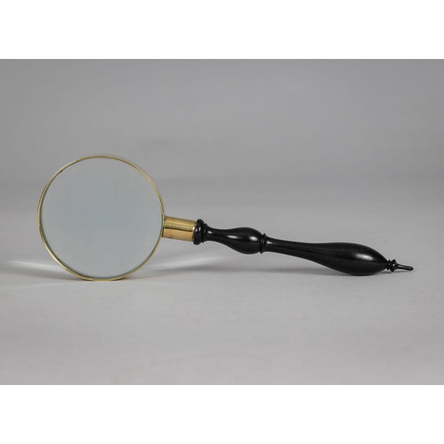 Antique magnifying glass with a turned ebony handle, brass frame and collar.