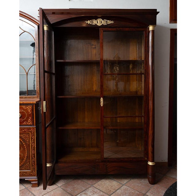 Two-door Empire bookcase in mahogany crotch with gilded bronze inserts, dating back to the early 19th century. The front...