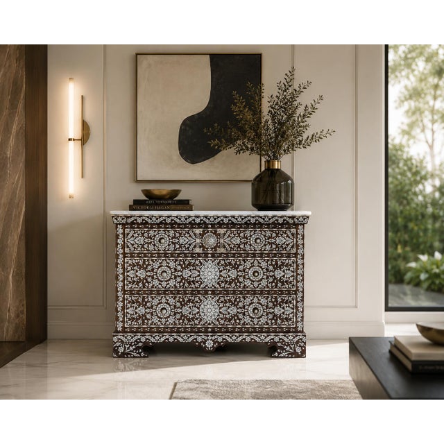 An exceptional handcrafted chest of drawers featuring intricate mother-of-pearl inlay and a natural marble top. Rich...