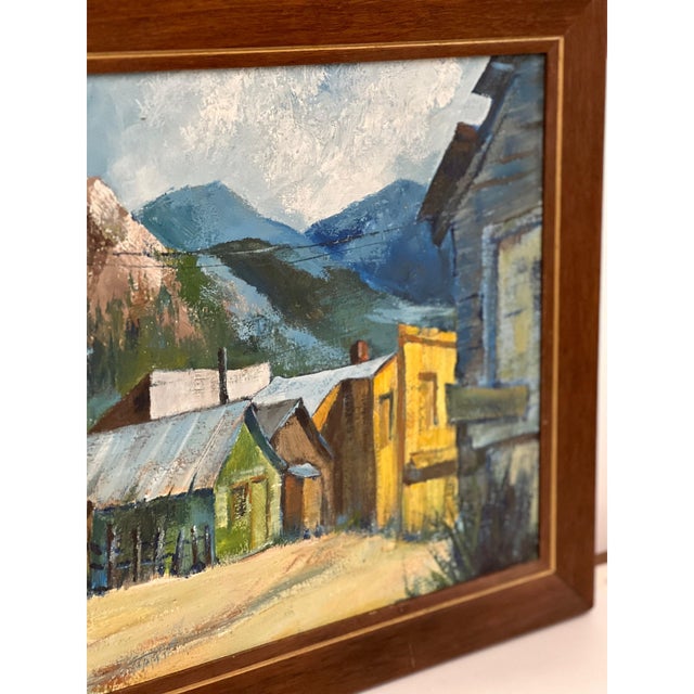 Vintage landscape painting depicting a rustic mountain town set against a backdrop of alpine peaks. The composition...
