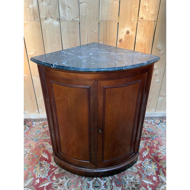 A Louis-Philippe period corner cabinet in mahogany and mahogany veneer on an oak frame, with a quarter-circle shape...