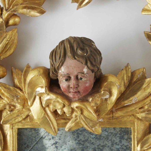 Gilded Mirror with Cherub, 1800. The square frame is surmounted by the head of a winged cherub, framed by a rich garland...