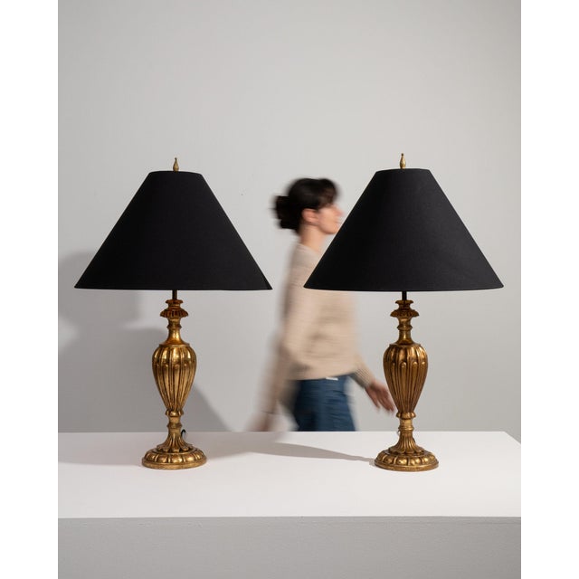 Pair of brass urn table lamps in Antique Brass. Finished in antique brass, this pair of brass urn table lamps is...