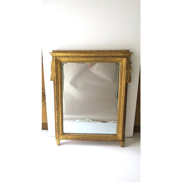 A gold giltwood wall mirror in the Neoclassical design style, circa late-19th century, Europe. The Empire period was...