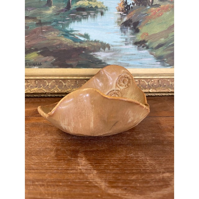 Vintage handmade bowl featuring an organic, freeform silhouette and soft earth-toned glaze. The interior is accented with...