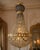 A striking late 20th-century French Louis XVI-style chandelier, featuring a sculptural gold-toned framework wrapped with...