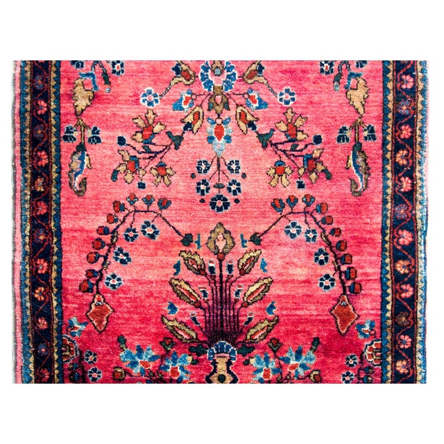 A stunning early 20th century Persian Sarouk Mohajeran rug with a mirrored floral and vine pattern woven in pink, light...