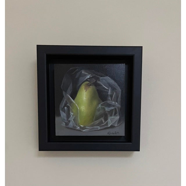 This oil painting depicts a pear nestled within crumpled plastic, creating a striking contrast between the organic form of...