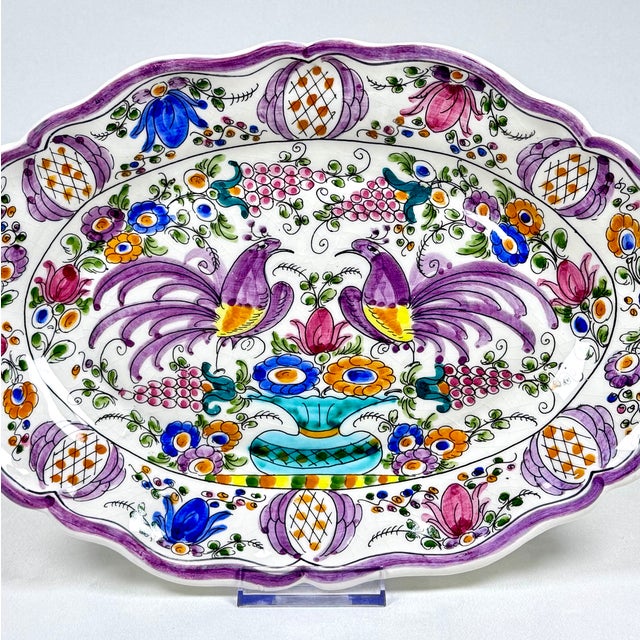 An antique hand-painted polychrome faience wall plate featuring a richly decorated composition of stylized birds, flowers,...