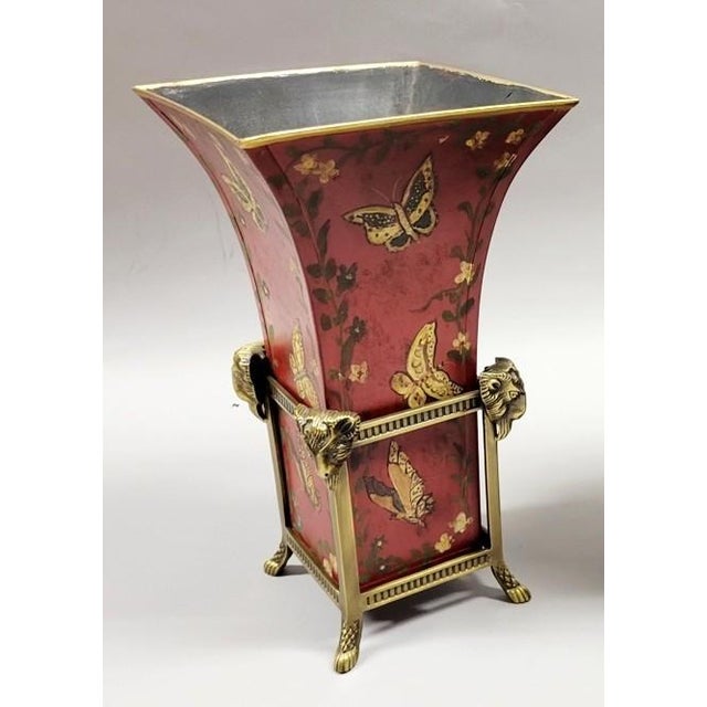 A striking decorative vase featuring a rich oxblood-red tole vessel hand-painted with butterflies, trailing vines, and...
