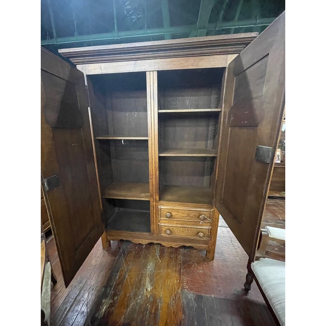 Antique oak armoire featuring carved floral panels, paneled doors, and classic French Provincial proportions. Interior...
