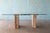 A postmodern dining table attributed to Artedi. Travertine bases linked with a chrome bar supporting a glass top. This...