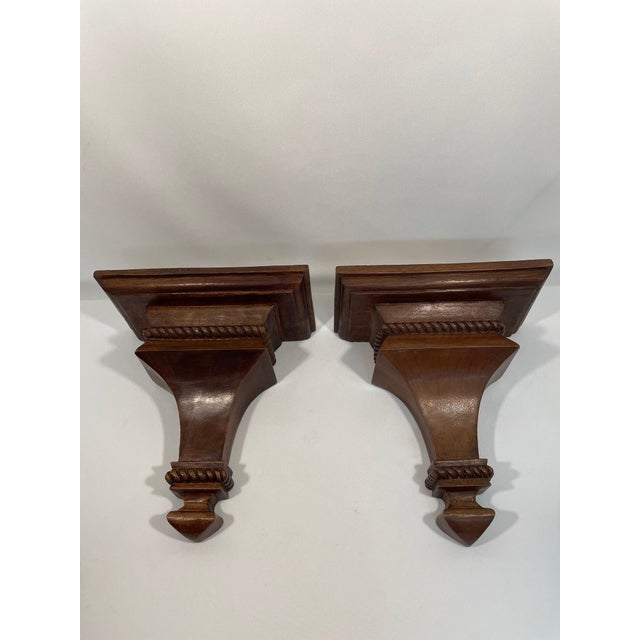 A handsome pair of hand carved Neoclassical Style wooden Corbels Wall Shelf Brackets with a rich walnut stain. Circa Mid...